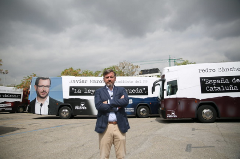 Arsuaga in front of buses carrying ads against Vox's opponents.