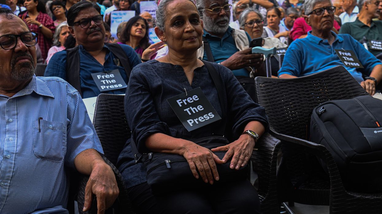 Arundhati Roy attends a demonstration wearing a small "Free the Press" sign.