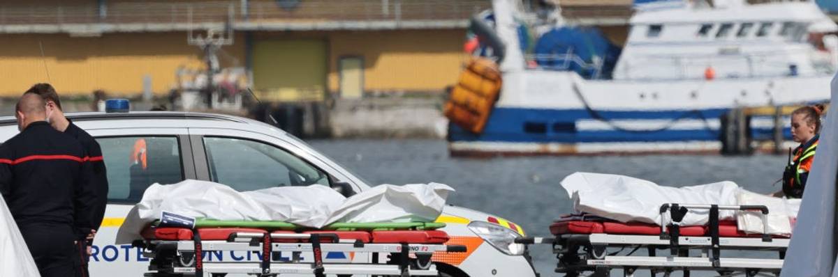Authorities stand next to bags containing the bodies of migrants who died