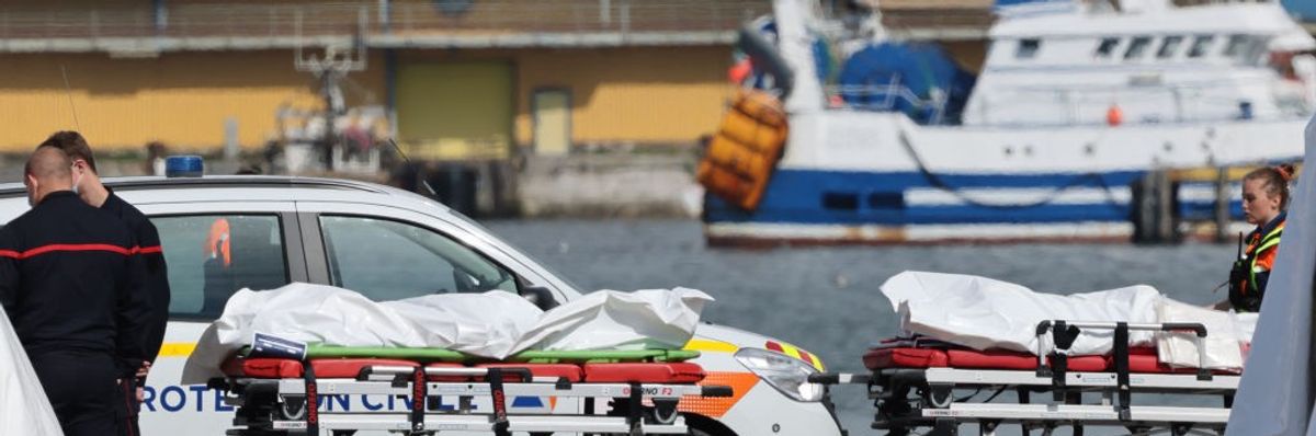 Authorities stand next to bags containing the bodies of migrants who died