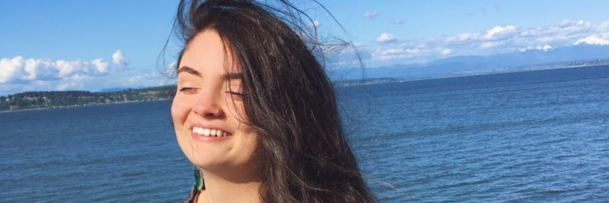 Ayşenur Ezgi Eygi smiles on a sunny day while standing next to a large body of water.