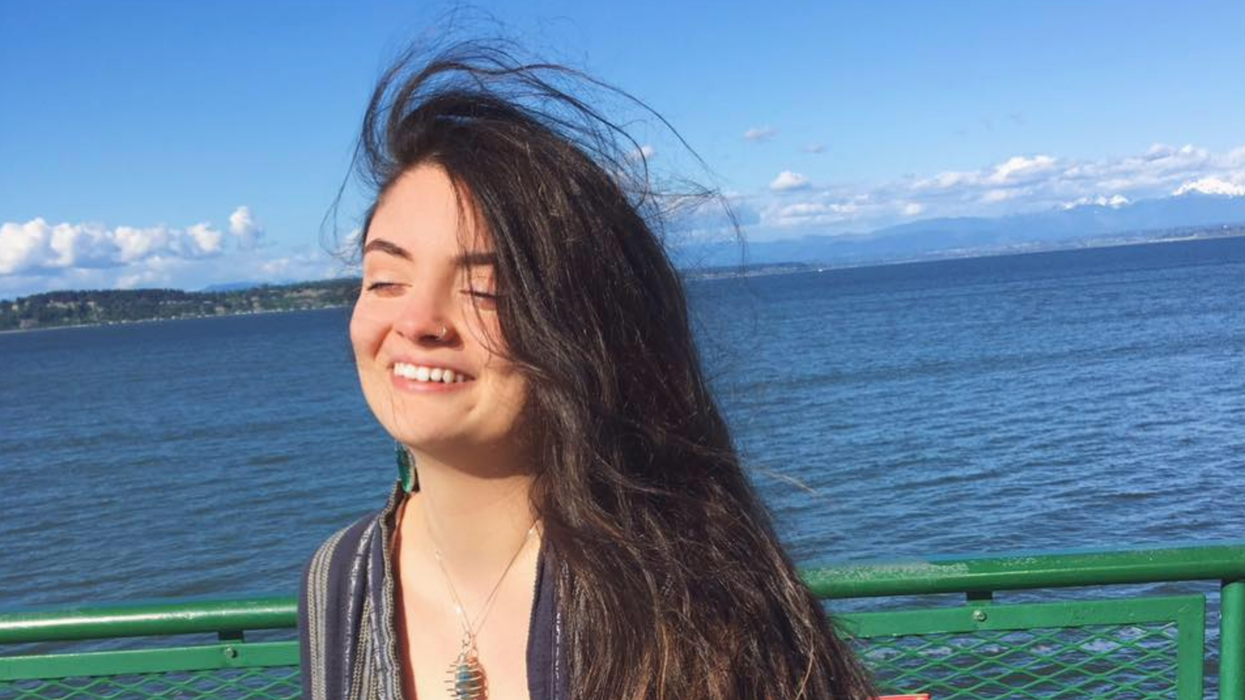 Ayşenur Ezgi Eygi smiles on a sunny day while standing next to a large body of water.