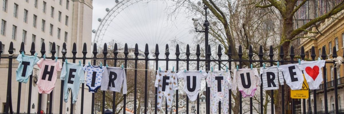 Baby clothes with letters spelling out "Their future" are strung over a gate.