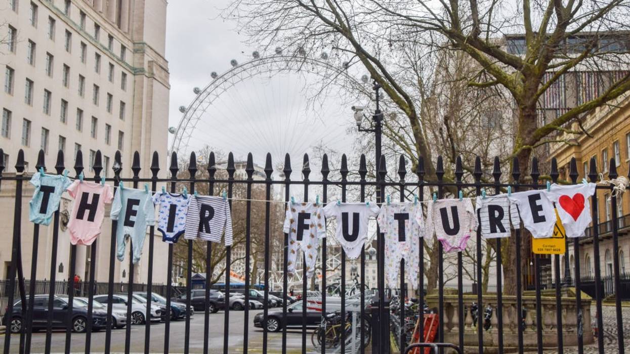 Baby clothes with letters spelling out "Their future" are strung over a gate.