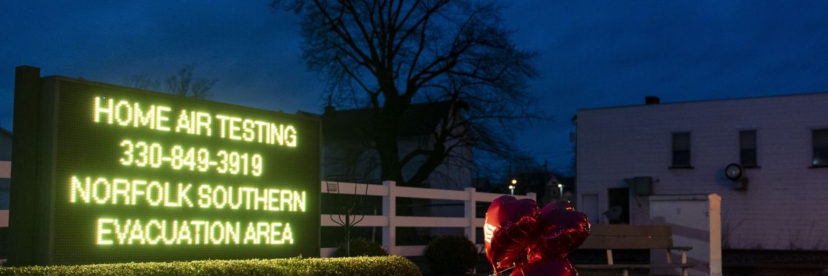 Balloons are placed next to a sign displaying information for residents to receive air-quality tests