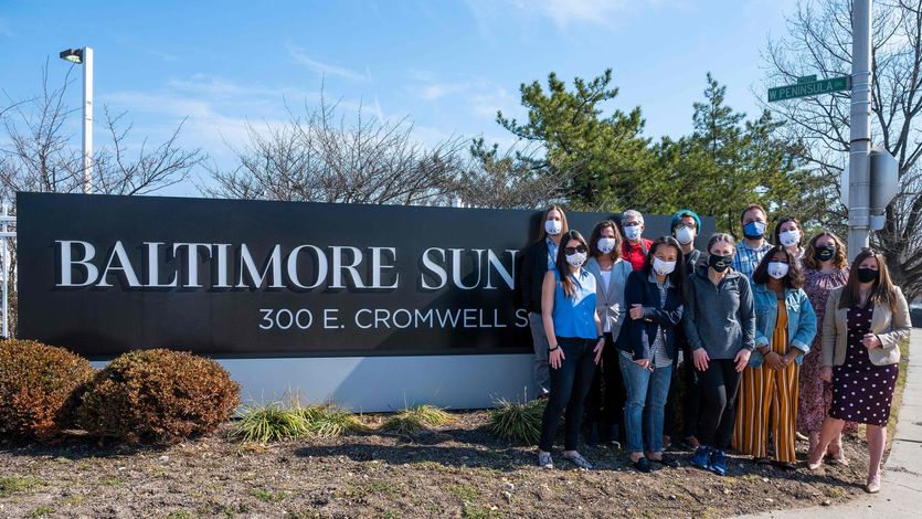 Baltimore Sun staff pose in front of the Sun sign.