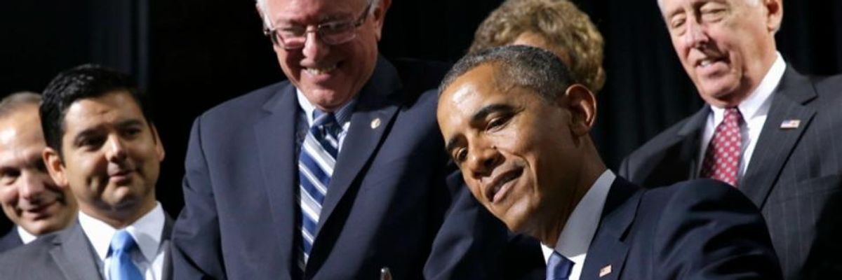 Bernie Sanders smiles as then-President Barack Obama signs a bill into law
