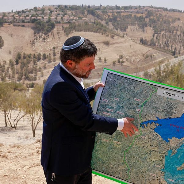 Bezalel Smotrich holds a map of an area in the illegally occupied West Bank of Palestine