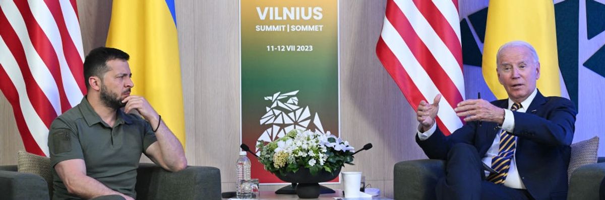 Biden and Zelensky sit in chairs facing each other.