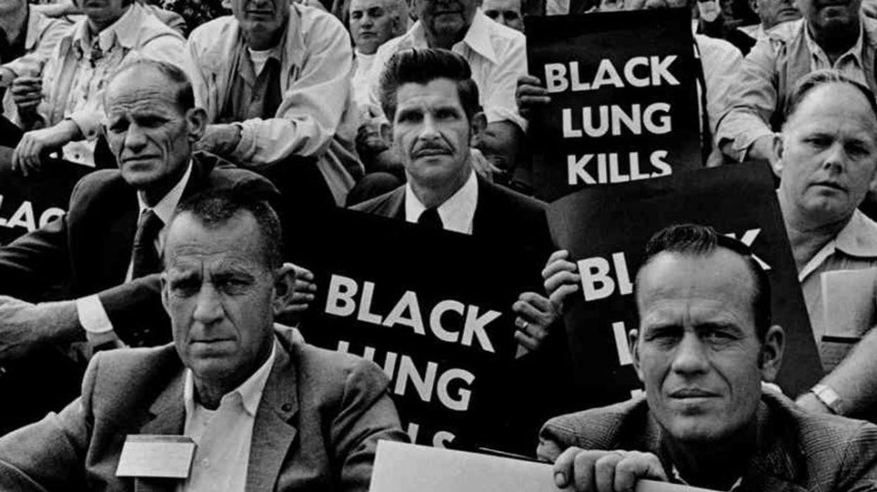 Black and white image of miners holding signs reading, "Black lung kills."