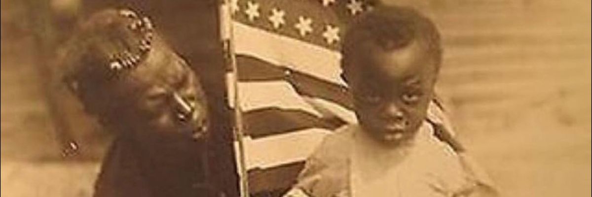 Black mother and child hold American flag after the end of the Civil War.