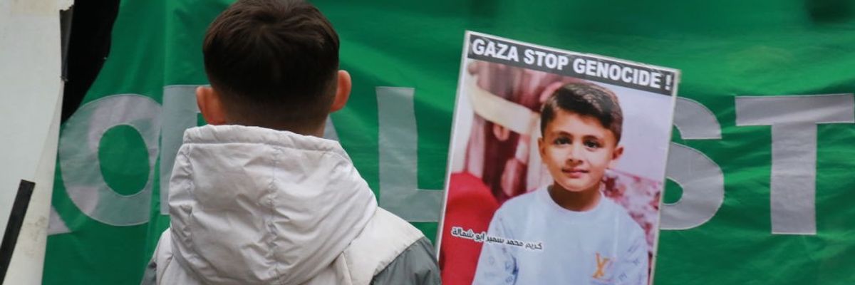 Boy in France holds signs that reads "Gaza Stop Genocide!"