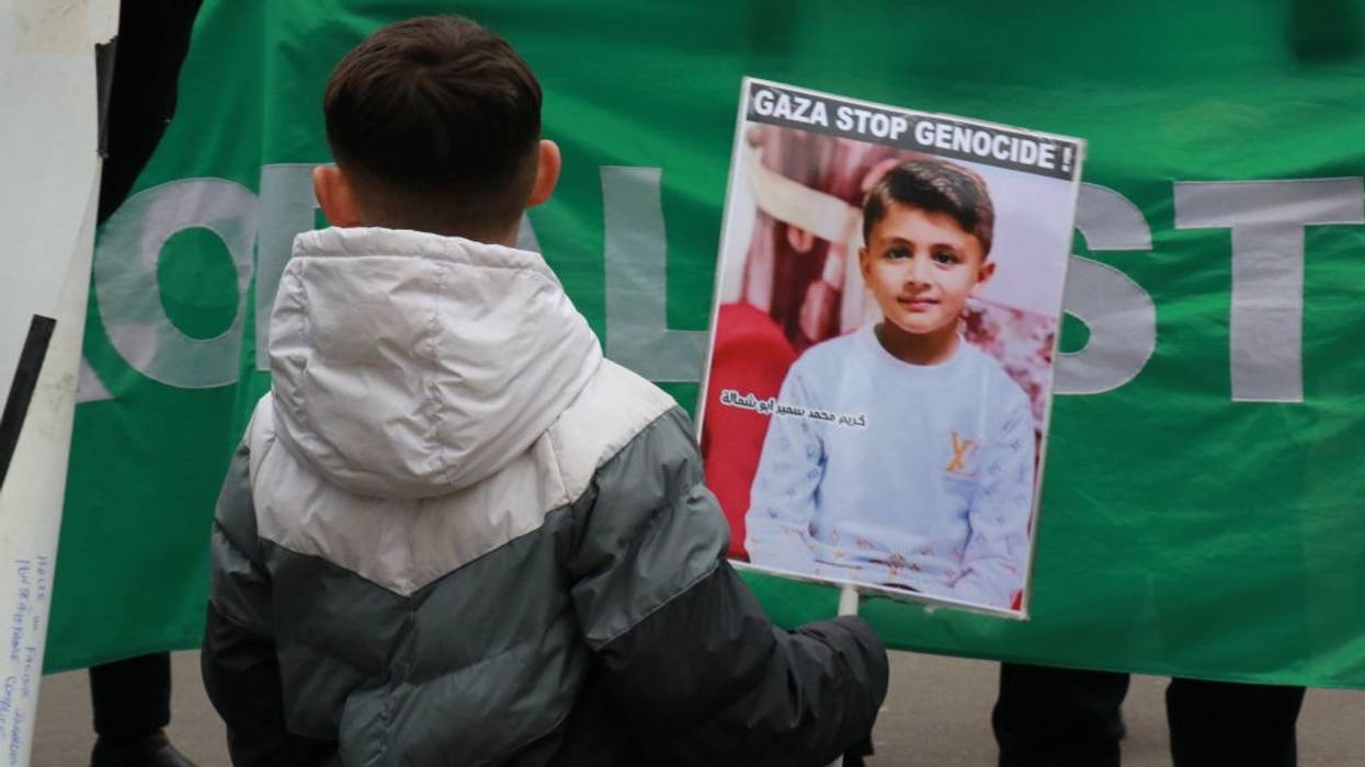 Boy in France holds signs that reads "Gaza Stop Genocide!"