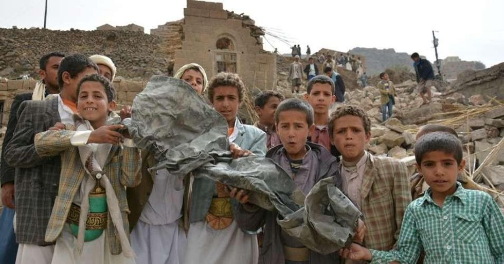 Boys hold a large piece of twisted metal near homes that were destroyed in an air strike in Okash Village, near Sana'a, the capital of Yemen in 2017. (Photo: UNICEF/Mohammed Hamoud)