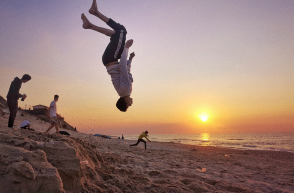 Boys leap in the air at the beach, part of photographer Majd Arandas' mission to show the 