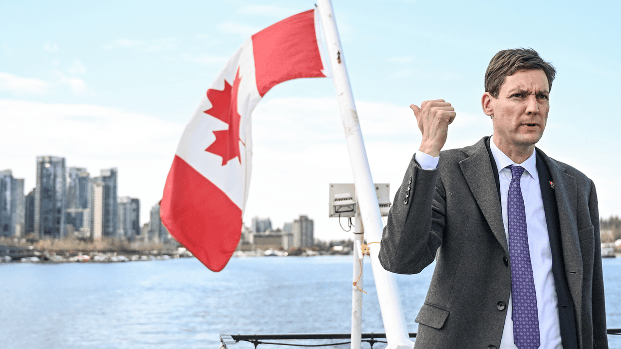 British Columbia Premier David Evy gestures toward a Canadian flag