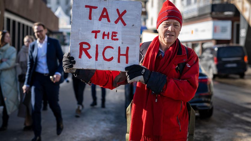 British millionaire, poses with a placard reading "Tax the rich"