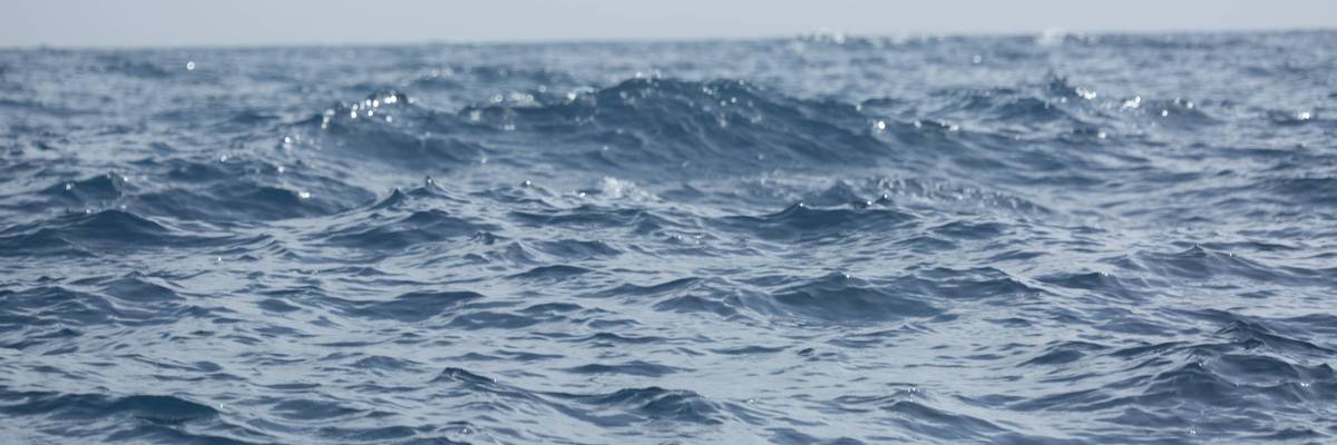 Calm Blue Ocean Water with Sparkling Sunlight Reflections and Hazy Horizon