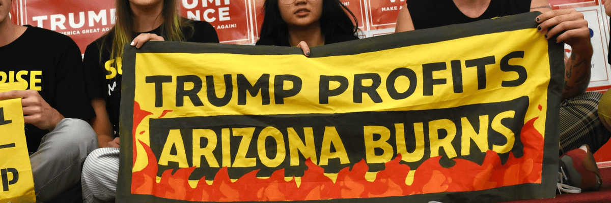 Campaigners hold a sign reading, "Trump Profits, Arizona Burns"