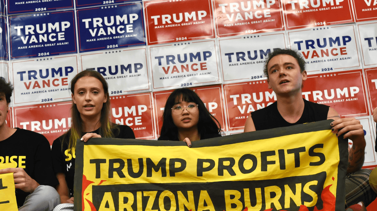Campaigners hold a sign reading, "Trump Profits, Arizona Burns"