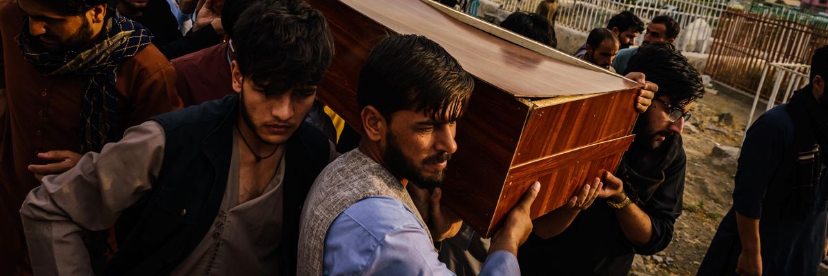 Caskets for the dead are carried towards the gravesite as relatives and friends attend a mass funeral for members of a family that is said to have been killed in a U.S. drone airstrike, in Kabul, Afghanistan, Monday, Aug. 30, 2021.