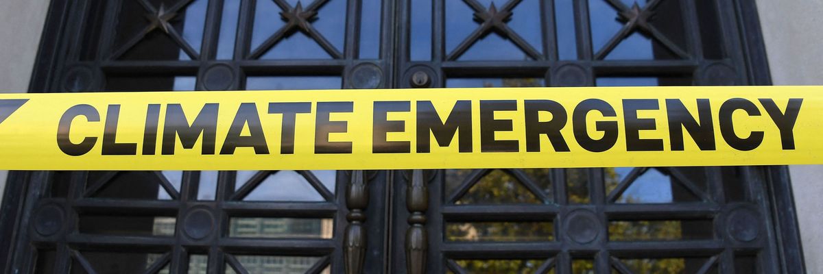 Caution tape reading Climate Emergency is placed outside the DOI.