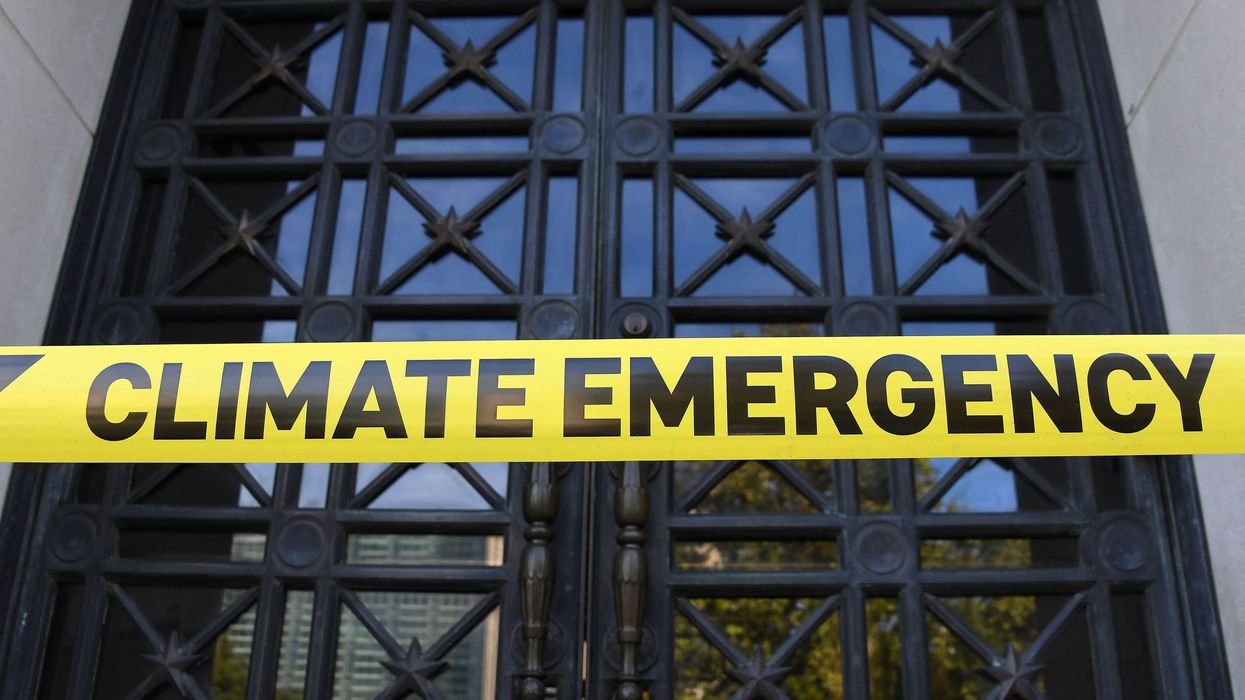Caution tape reading Climate Emergency is placed outside the DOI.