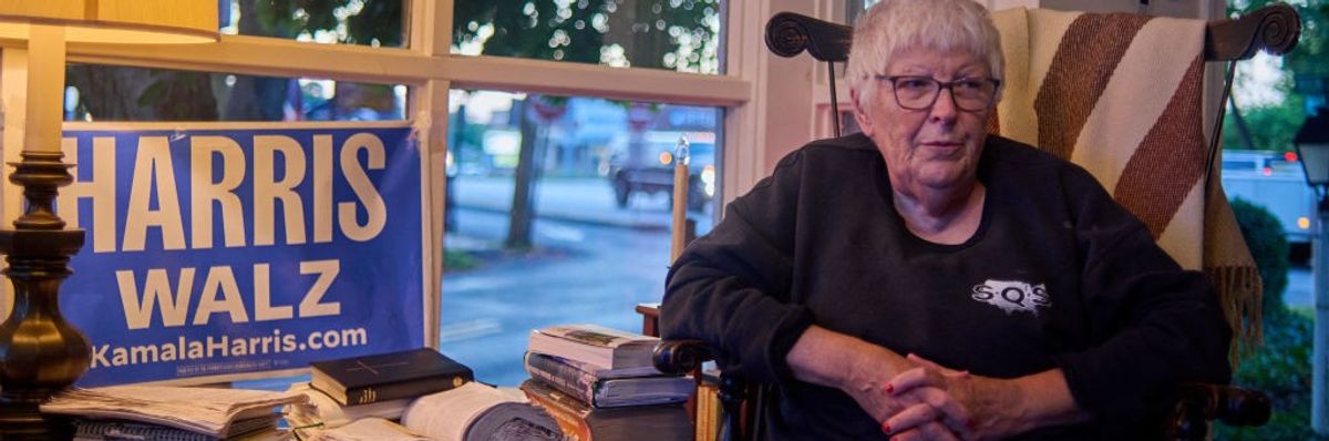 Charlene Sanger sits in her living room with a sign supporting Kamala Harris