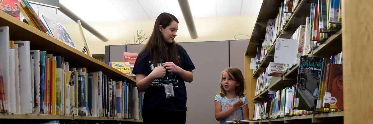 Child and librarian looking for books