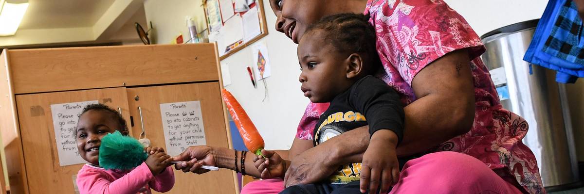 Child care worker Debbie James-Dean sits with children at a Kids Are Us Learning Center