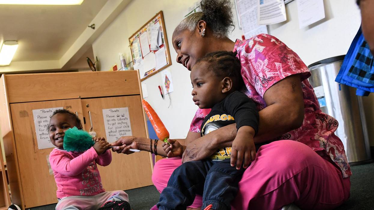 Child care worker Debbie James-Dean sits with children at a Kids Are Us Learning Center