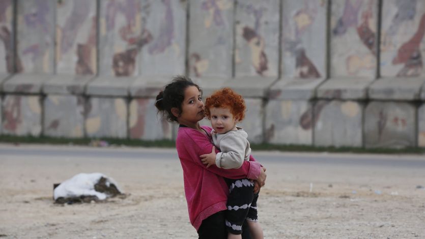 Child carries baby in rafah