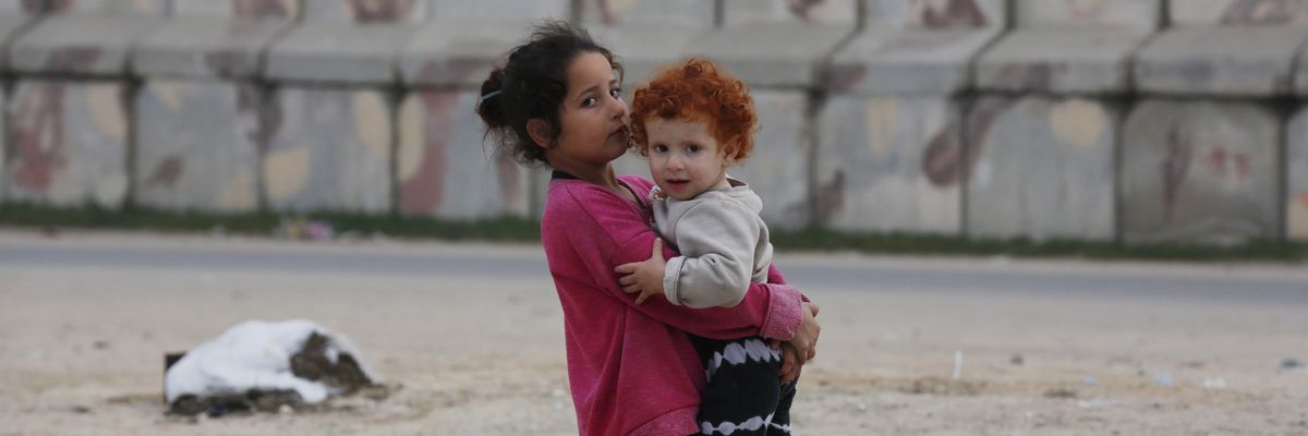 Child carries baby in rafah