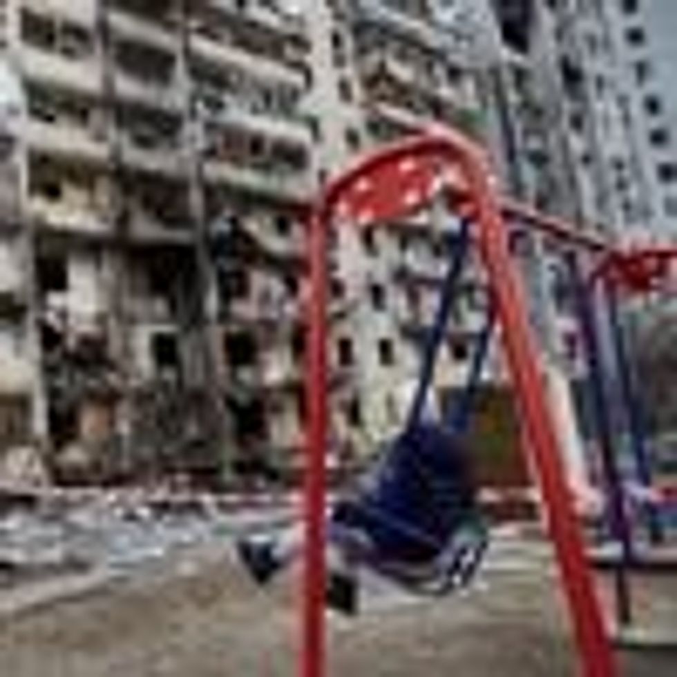 child on swing in front of destroyed building