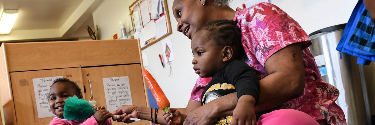 Childcare worker sits with children