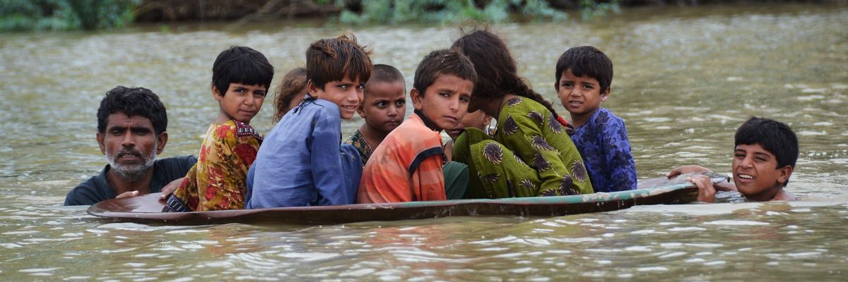 Children are helped across a flooded area in Pakistan's Balochistan province after catastrophic monsoon rains continued on August 26, 2022.