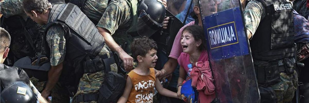 Children cry as refugees waiting on the Greek side of the border break through a cordon of Macedonian special police forces