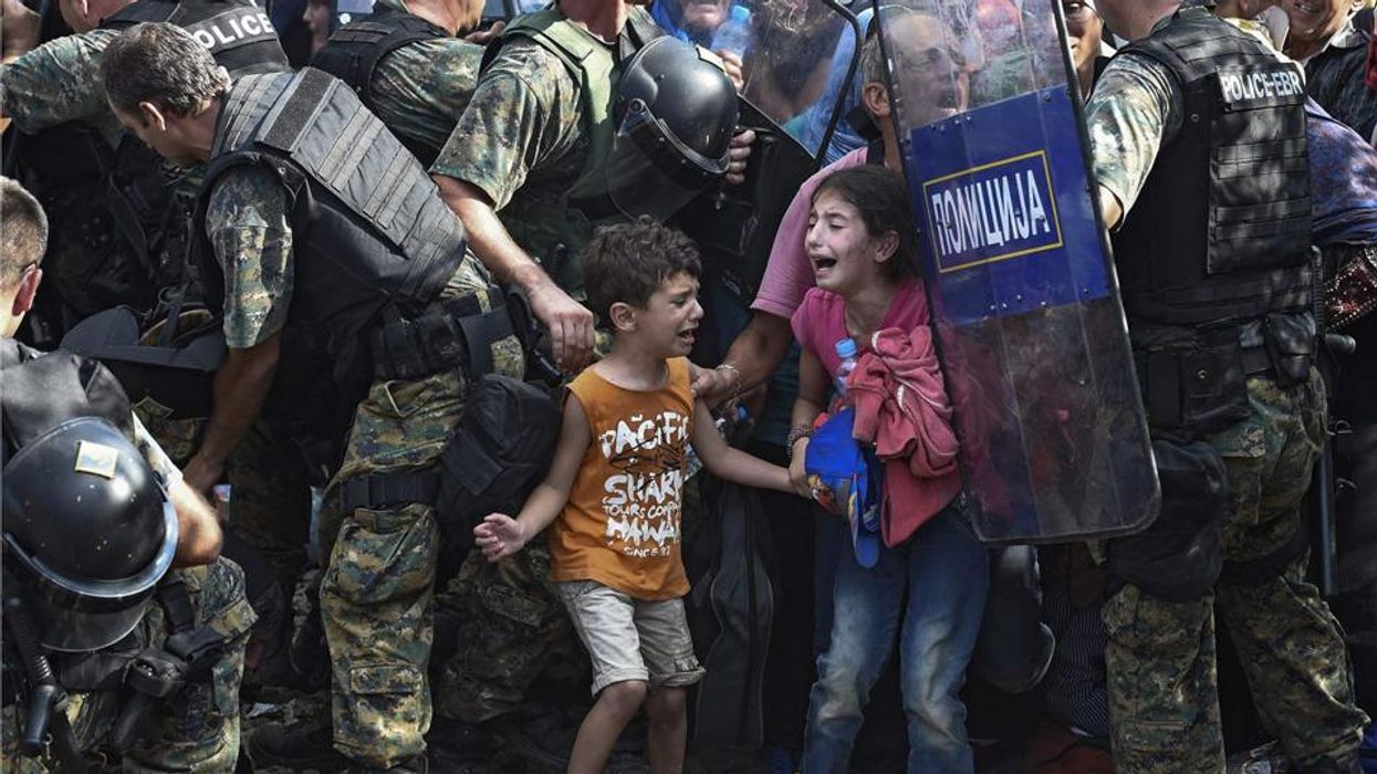 Children cry as refugees waiting on the Greek side of the border break through a cordon of Macedonian special police forces