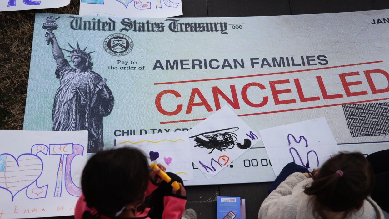 Children draw on a "cancelled check" prop at a rally for the child tax credit