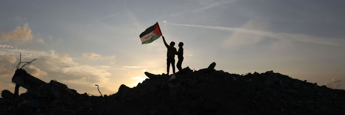 Children hold a Palestinian flag atop a mound of rubble in Gaza