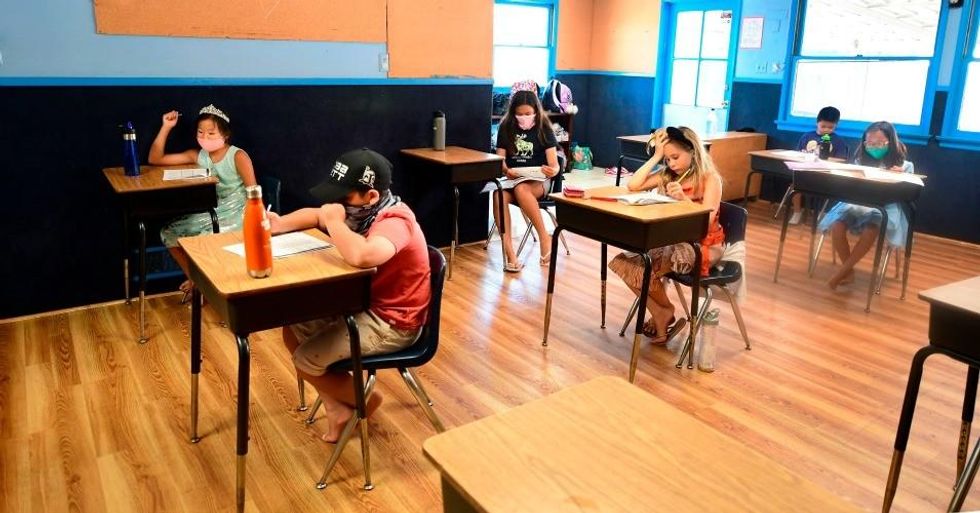 Children in an elementary school class wear masks and sit as desks spaced apart as per coronavirus guidelines during summer school sessions at Happy Day School in Monterey Park, California on July 9, 2020. (Photo: Frederic J. Brown/AFP via Getty Images)