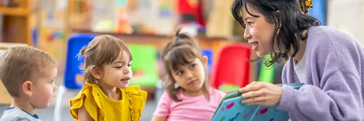 Children listen while teacher reads a book
