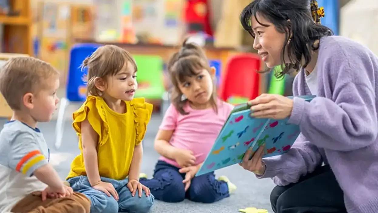 Children listen while teacher reads a book