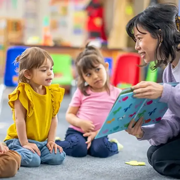 Children listen while teacher reads a book