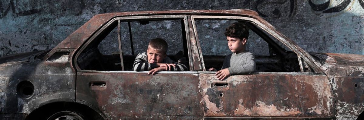 Children sit in a destroyed car in Gaza