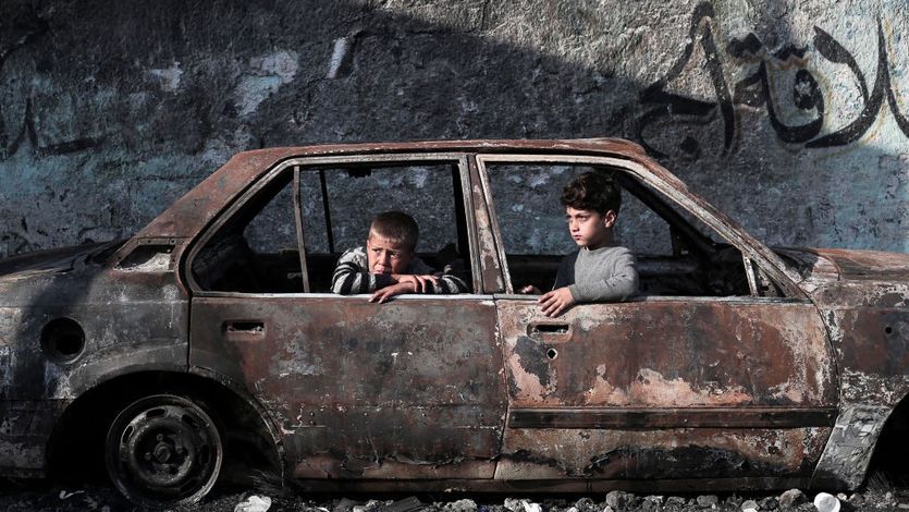 Children sit in a destroyed car in Gaza