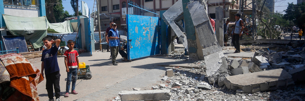 Children stand near the destruction of a facility