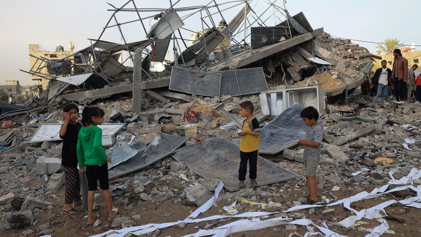 Children stand with bombed solar panels in Gaza.