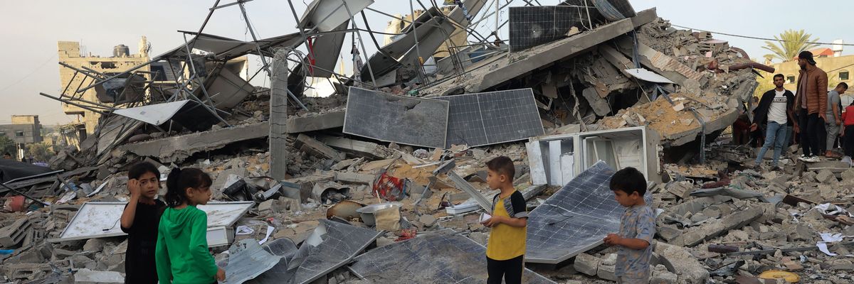 Children stand with bombed solar panels in Gaza.