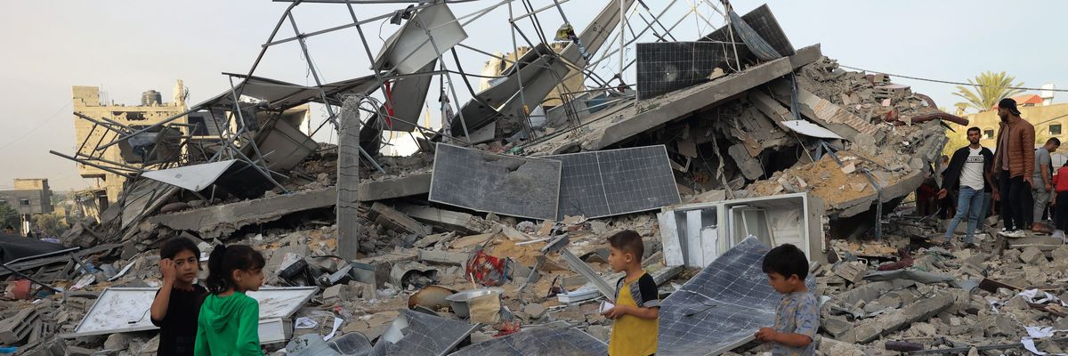 Children stand with bombed solar panels in Gaza.